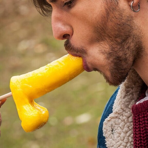 Gay brunette Victor A erotically sucks a sex toy lollipop on a public bench