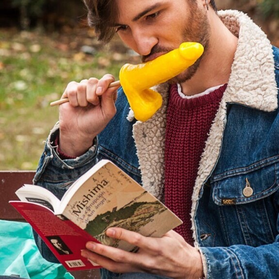 Gay brunette Victor A erotically sucks a sex toy lollipop on a public bench