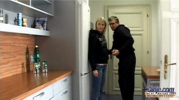 Un vieux monsieur séduit une jeune blonde mince à l'intérieur de la cuisine