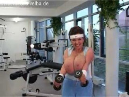 MILF sportive fait du sport avec l'intérieur du club de santé tout en étant seins nus