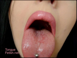 Impresionante mujer con piercing en la lengua indica sus talentos en primer plano