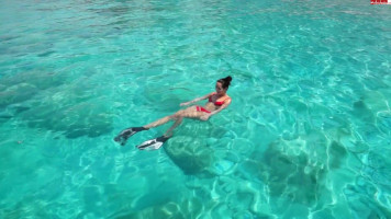 Wunderschöne Bikinifrau mit ausgezeichneten Klopfern reitet einen Schwanz am Strand