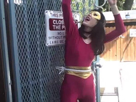 Black-haired milf in pink spandex overalls poses at the street